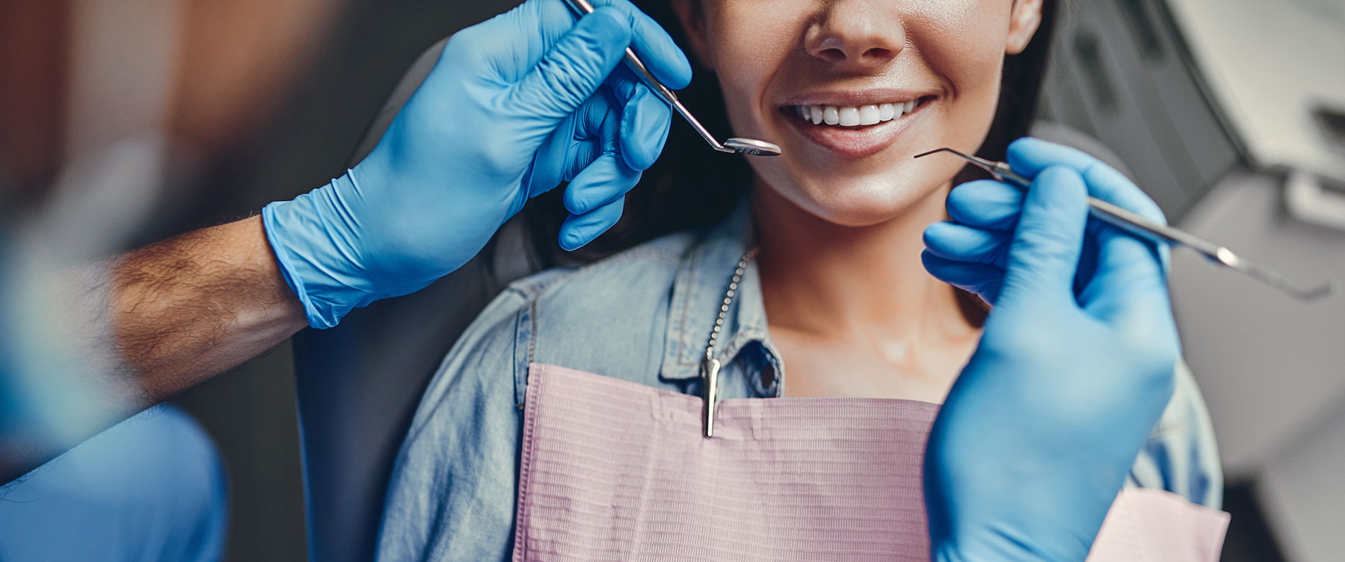 A woman receiving dental care with a smiling expression while a dental professional works on her teeth.