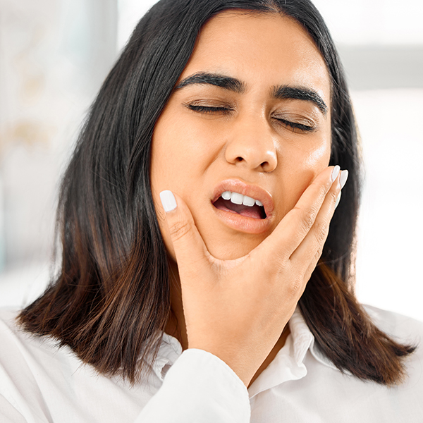 The image shows a person with short hair, wearing a black top, making a face with their hand on their chin, and appears to be yawning or stretching their mouth wide open.